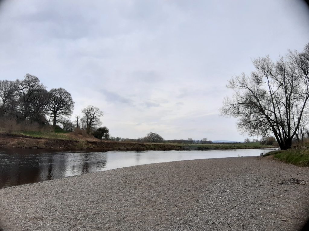 A shingle beach leading down tot he river Nith